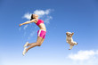 young woman and dog jumping in the sky